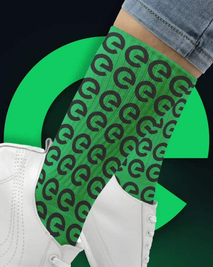 Calcetín con estampado de marca y tenis blancos sobre fondo verde